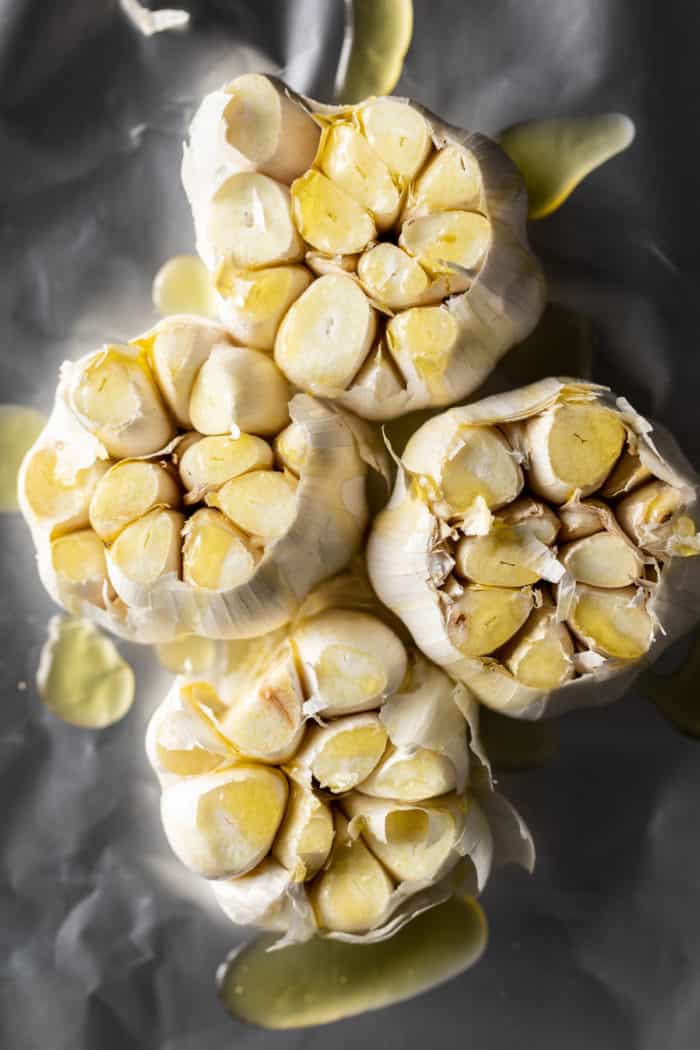 Heads of garlic with the tops cut off, drizzled with oil on a piece of foil.