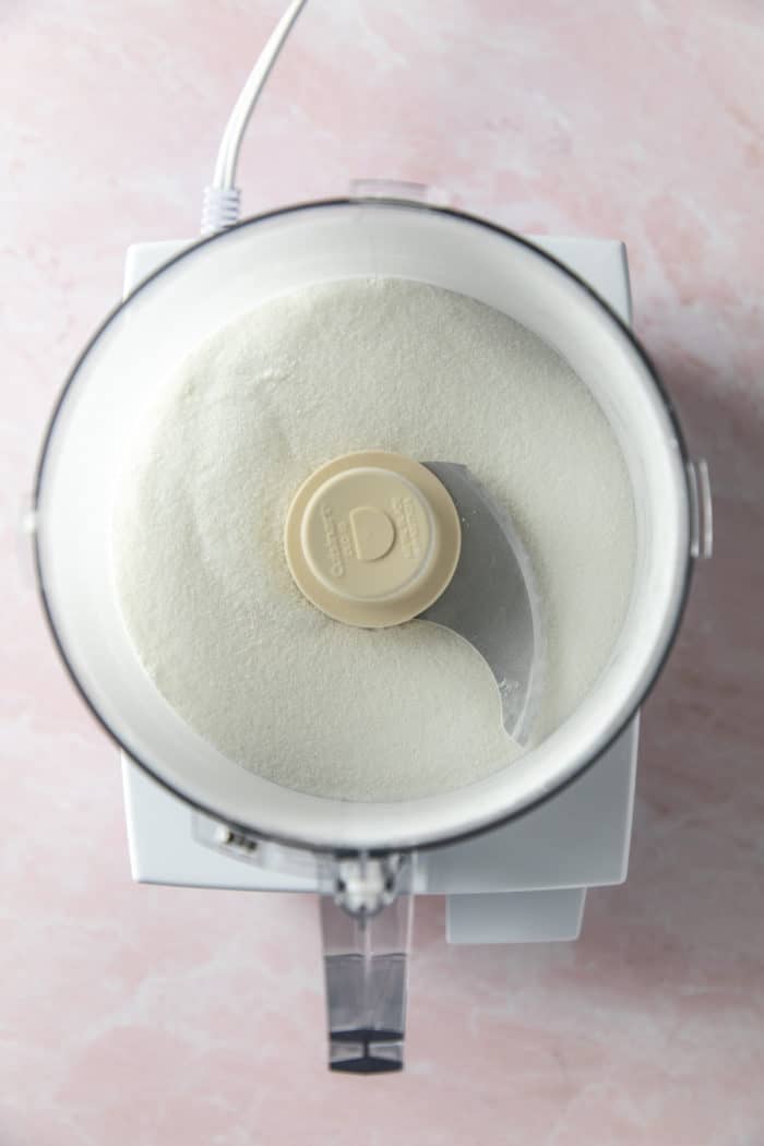 Granulated sugar being processed in the bowl of a food processor.