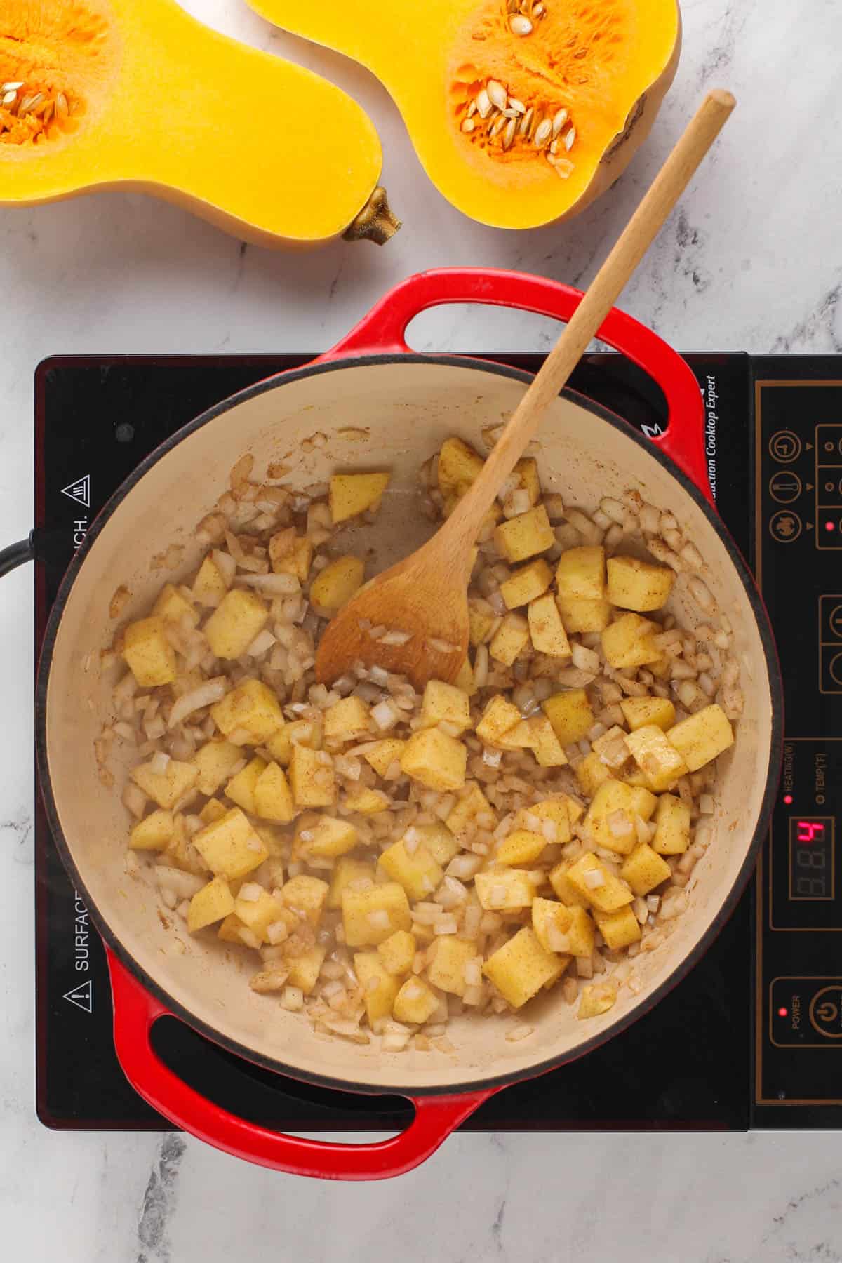 spices, apples and onions cooking in a red stock pot