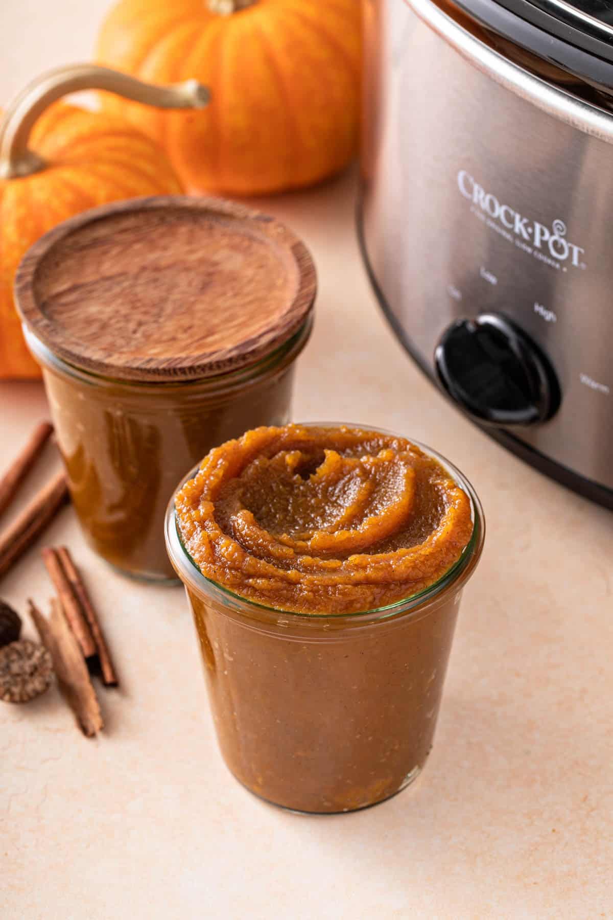 a slow cooker next to two jars of pumpkin butter