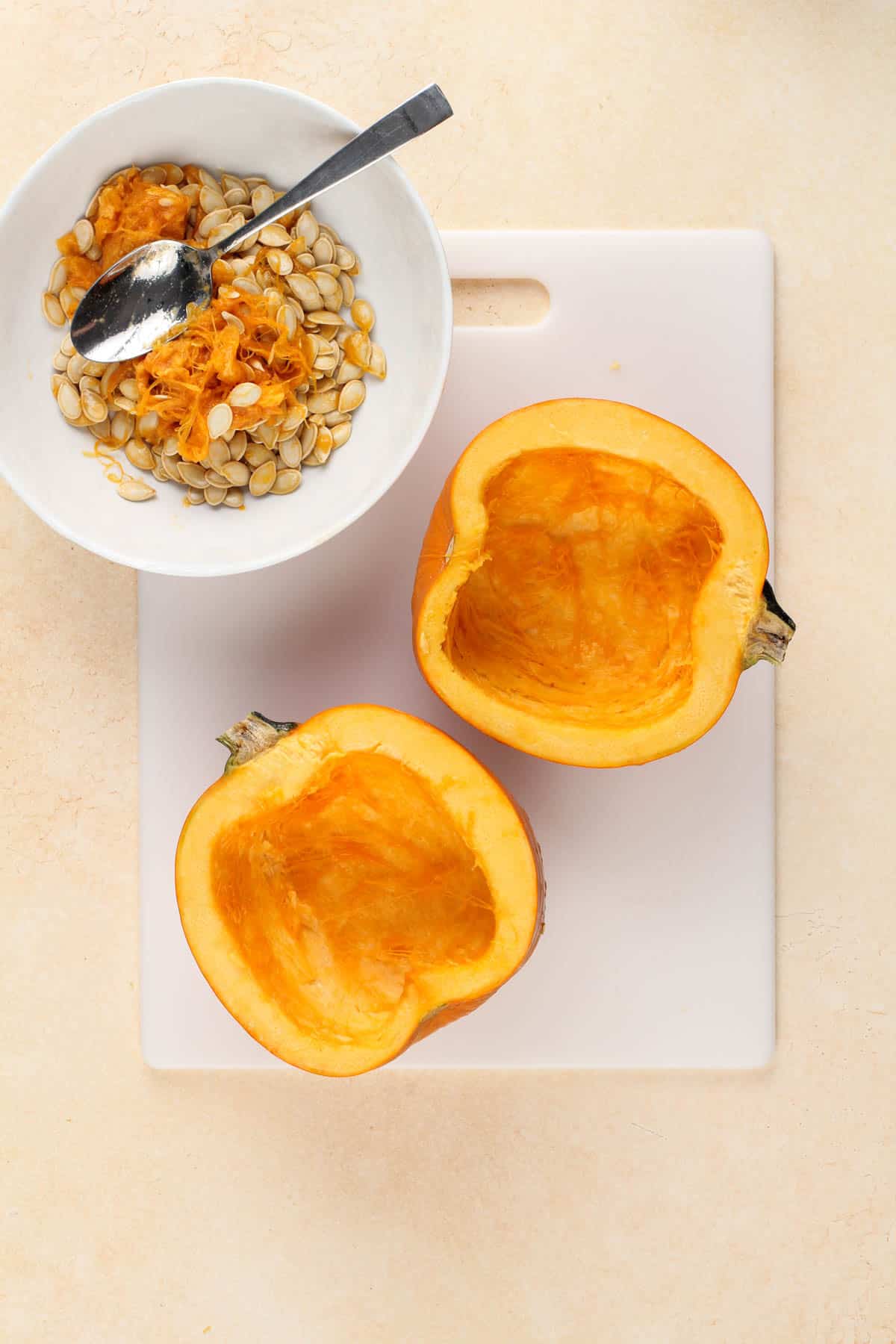 a pie pumpkin cut in half on a cutting board