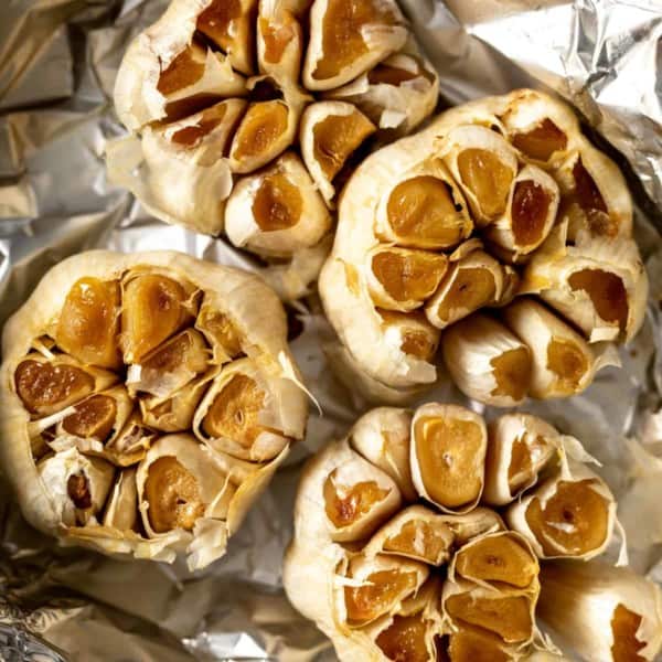 Close up of roasted heads of garlic on foil.