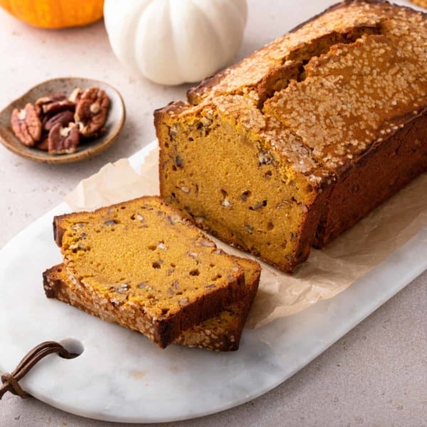 Sliced loaf of brown butter pumpkin bread on a marble board.