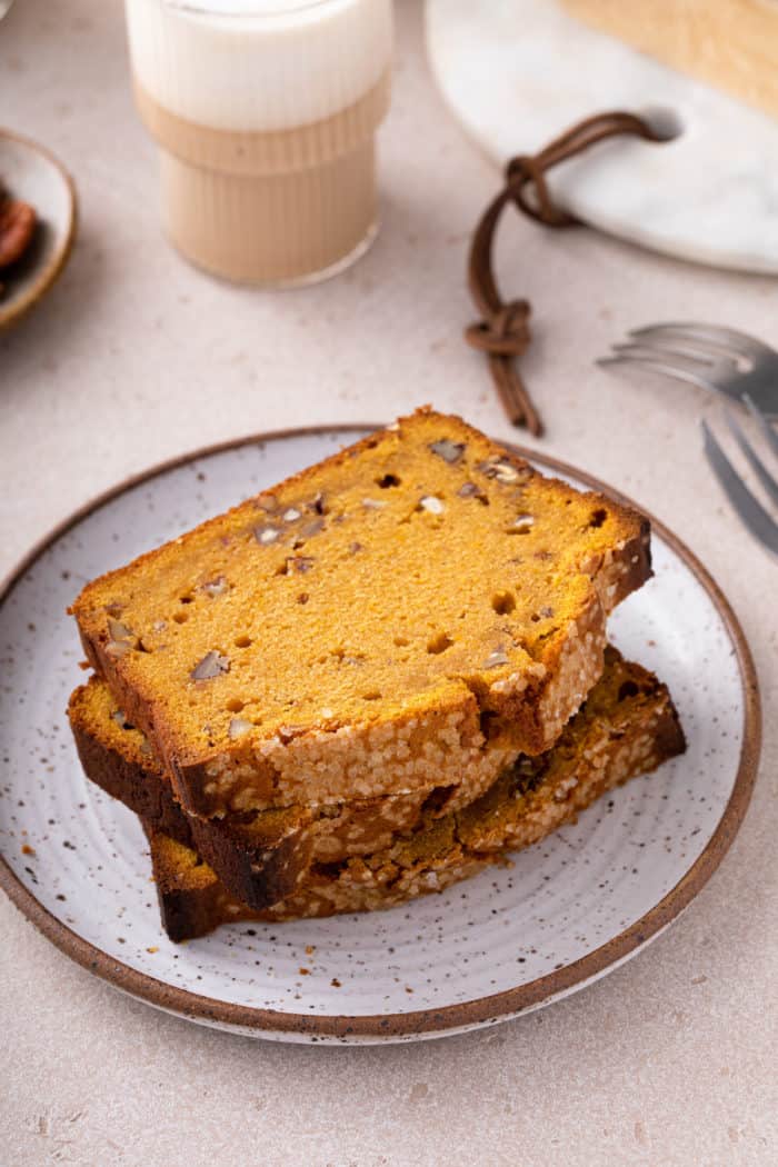 Three slices of brown butter pumpkin bread stacked on a plate.