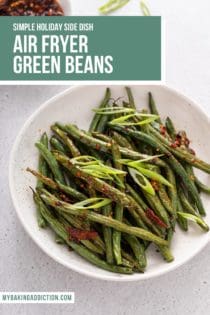 White serving bowl filled with air fryer green beans topped with chili crunch. Text overly includes recipe name.