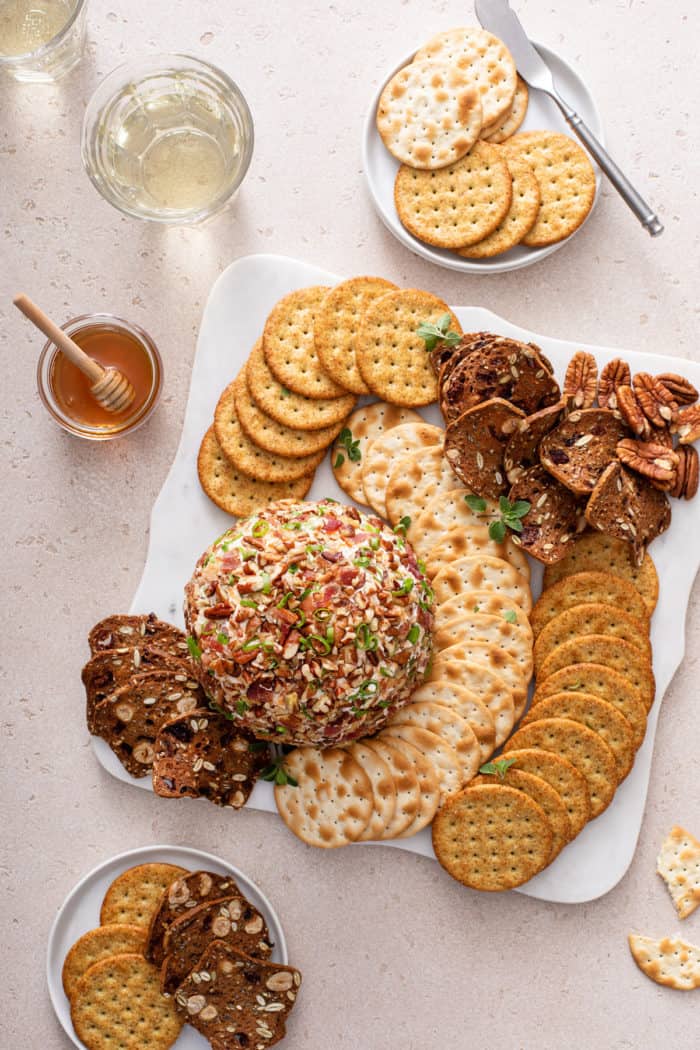 Overhead view of bacon ranch cheese ball surrounded by crackers on a white platter.
