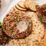 Bacon ranch cheese ball on a platter with a bite taken from it.