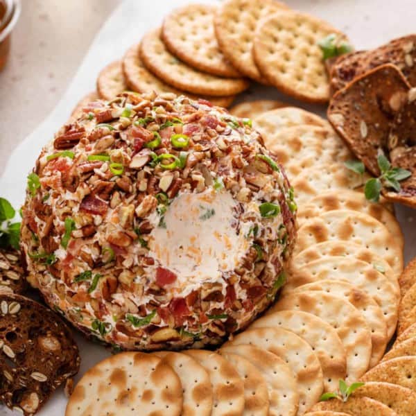 Bacon ranch cheese ball on a platter with a bite taken from it.