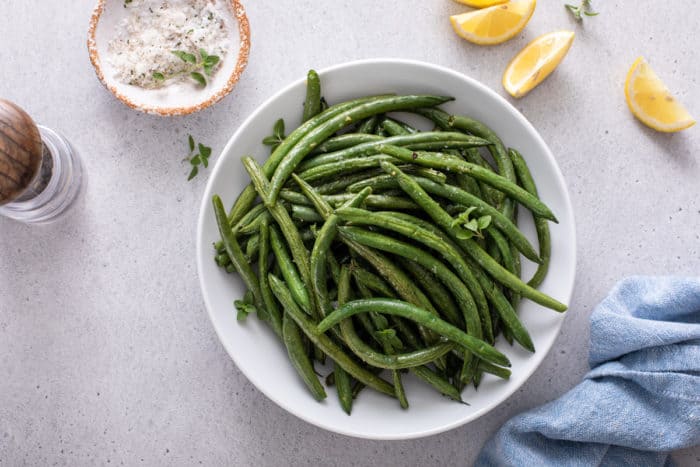 Overhead view of air fryer green beans in a white bowl.