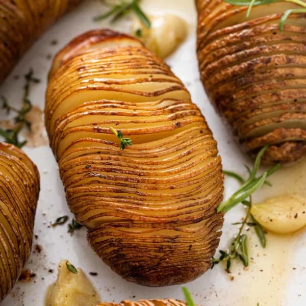 Close up of roasted hasselback potato in a baking dish.