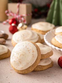 Two stacked eggnog cookies with a third leaning against the stack. More cookies are visible in the background.