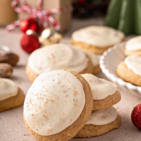 Two stacked eggnog cookies with a third leaning against the stack. More cookies are visible in the background.