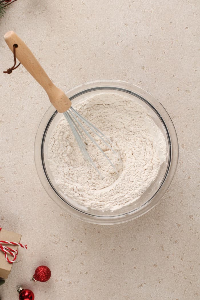 Dry ingredients for eggnog cookie dough being whisked together in a glass mixing bowl.