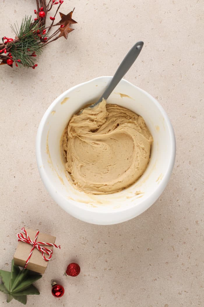 Eggnog cookie dough being mixed in a white mixing bowl.