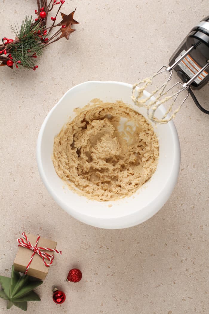 Wet ingredients for eggnog cookies being mixed in a white bowl.