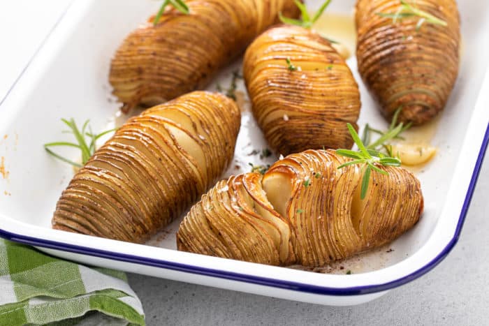 Roasted hasselback potatoes in a white baking dish.