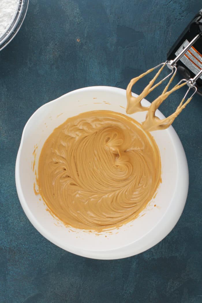 Butter and peanut butter mixed in a white mixing bowl.