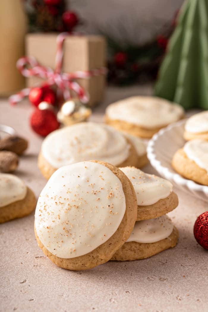 Two stacked eggnog cookies with a third leaning against the stack. More cookies are visible in the background.