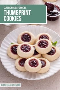 Raspberry thumbprint cookies piled onto a white plate. A glass of milk and a bowl of raspberry jam are visible in the background. Text overly includes recipe name.