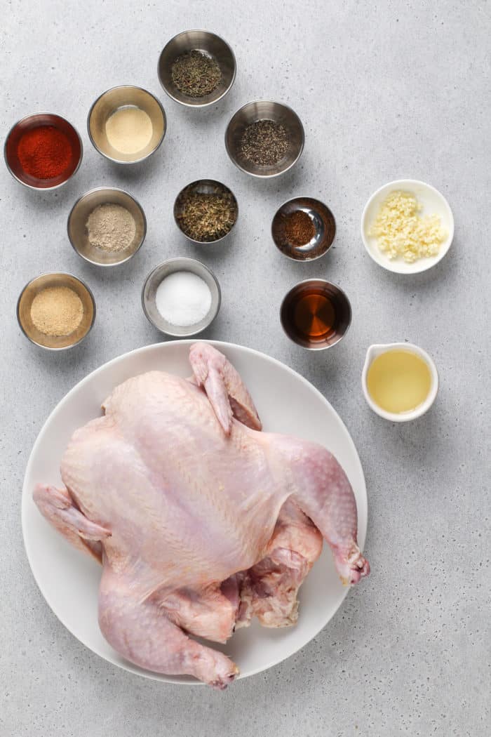 Ingredients for air fryer rotisserie chicken arranged on a gray countertop.