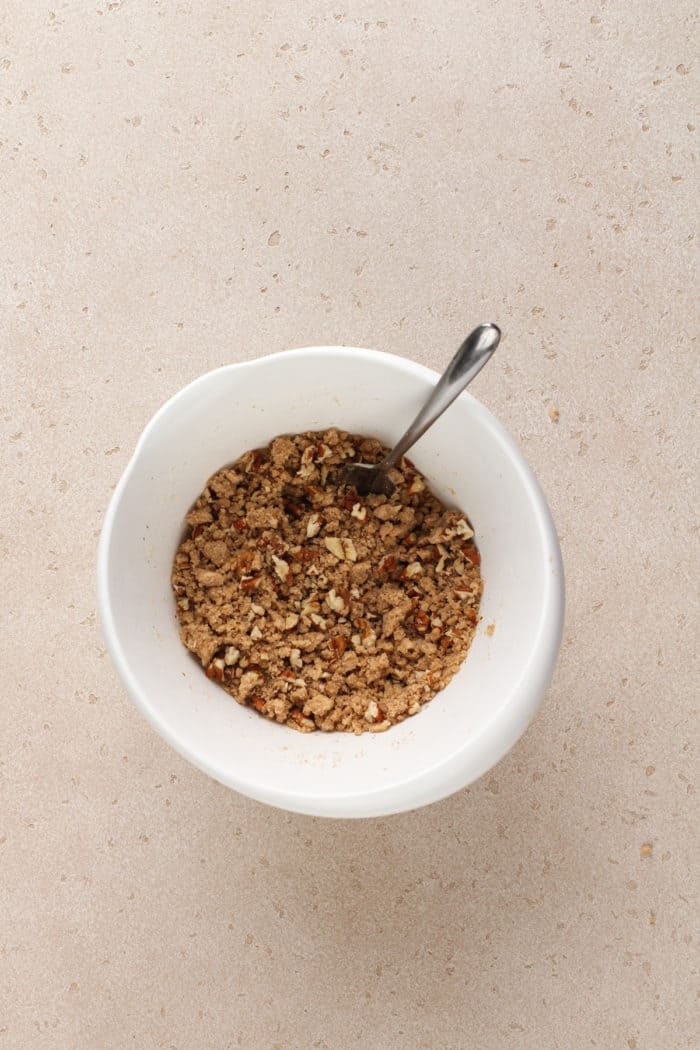 Streusel for Bisquick coffee cake being stirred in a small white mixing bowl.