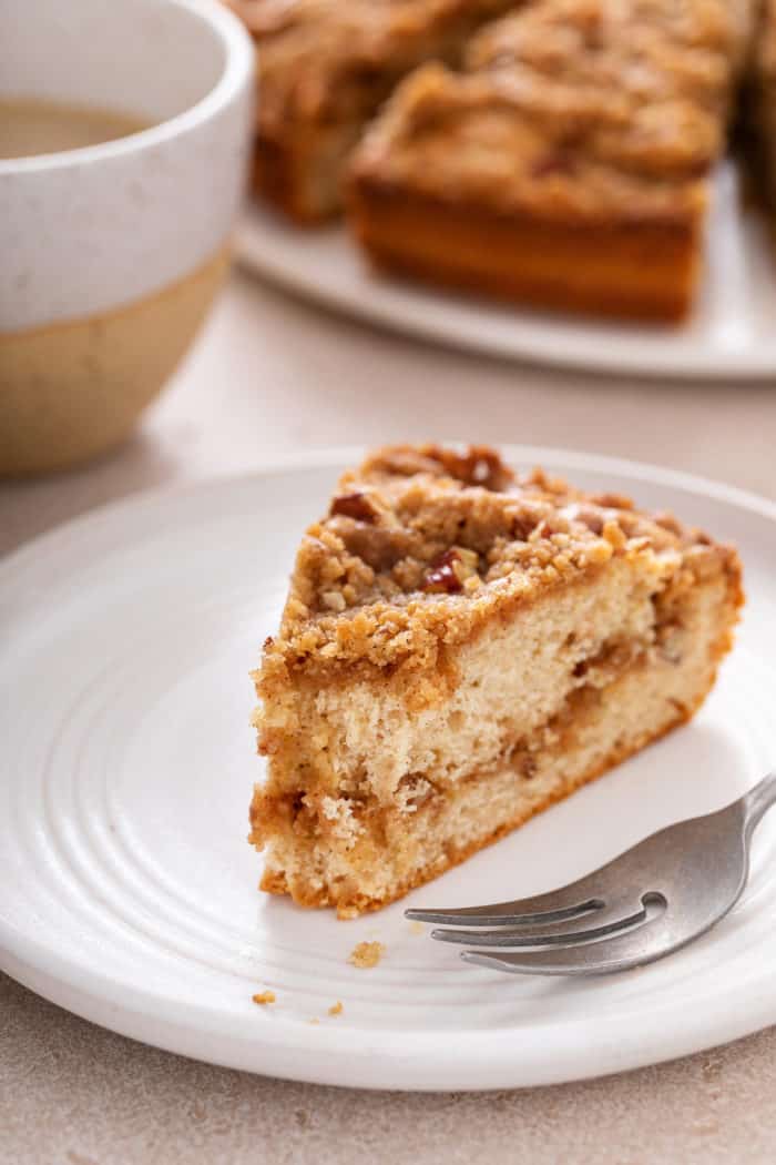 Slice of bisquick coffee cake on a white plate with a bite taken from the end of it. A fork is next to the cake on the plate.