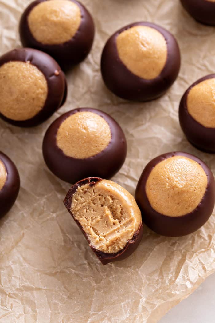 Several buckeyes arranged on a piece of parchment paper. A bite has been taken out of one of the candies.