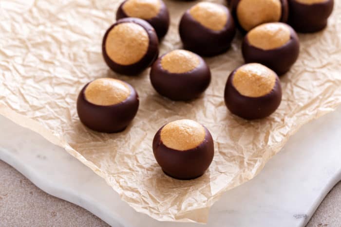 Several buckeye candies scattered on a piece of parchment paper.