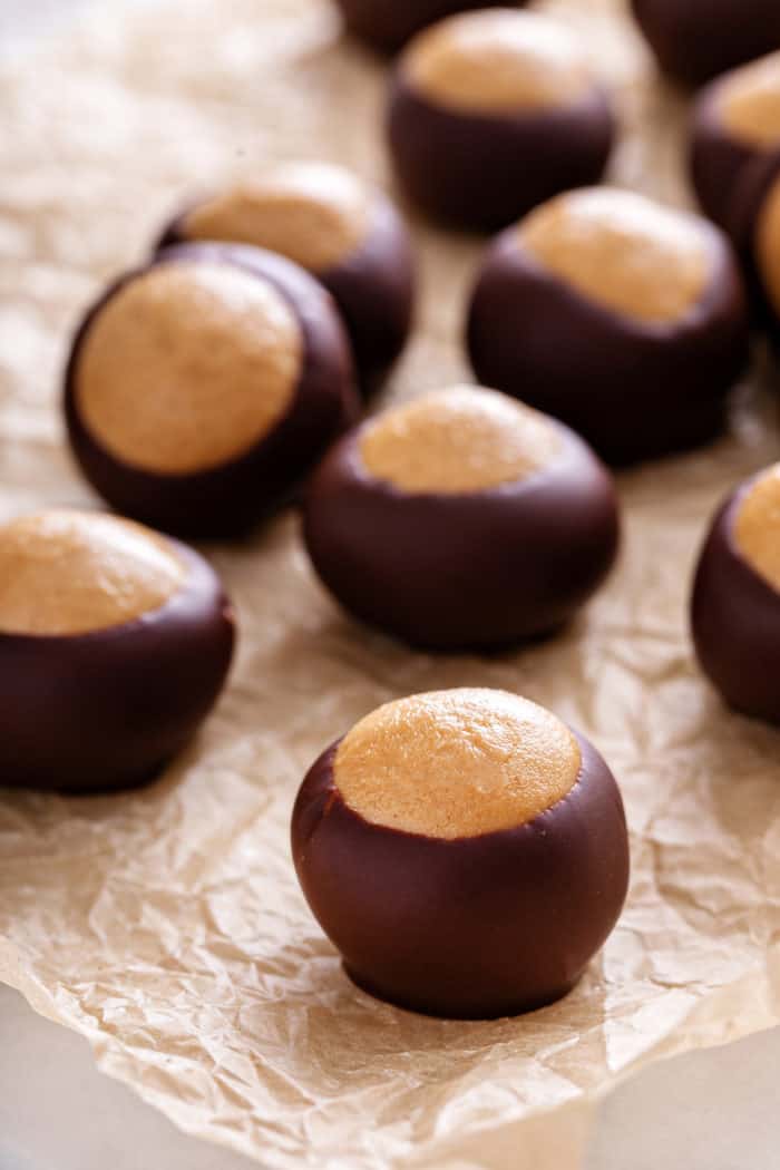 Close up of buckeye candies scattered on a piece of parchment paper.