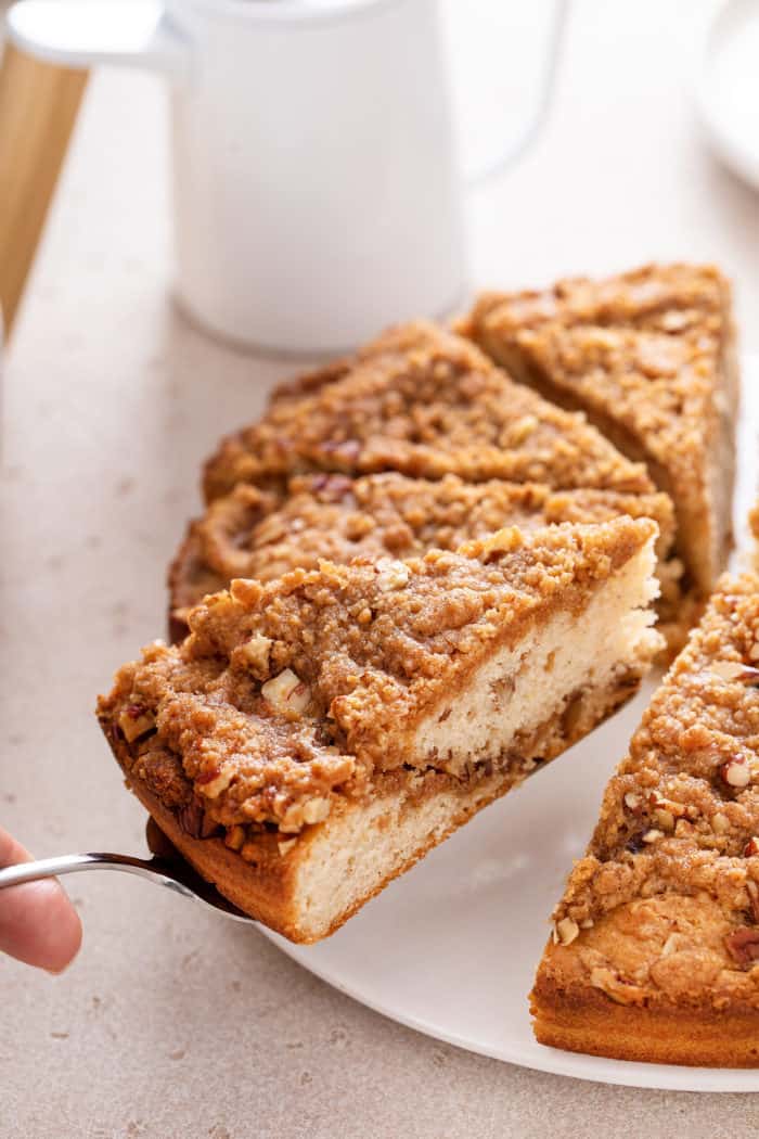 Cake server lifting a slice of bisquick coffee cake from a white cake plate.