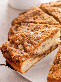 Cake server picking up a slice of bisquick coffee cake from a white cake plate.