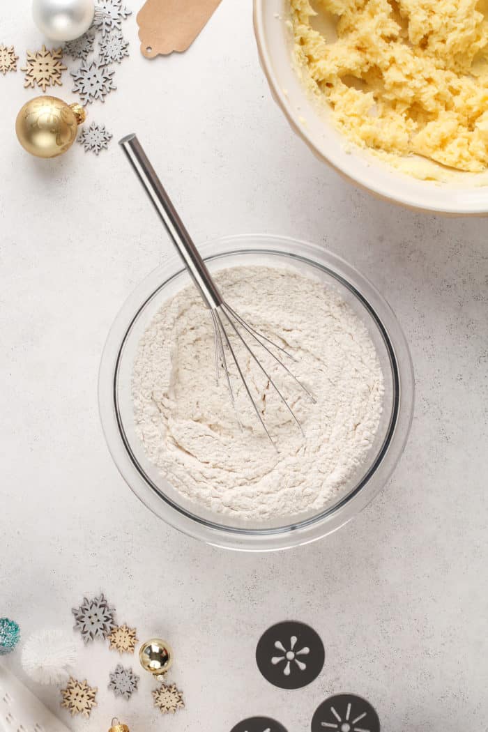 Dry ingredients for spritz cookies being whisked in a glass mixing bowl.