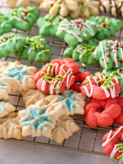 Winter holiday-themed spritz cookies on a wire cooling rack.