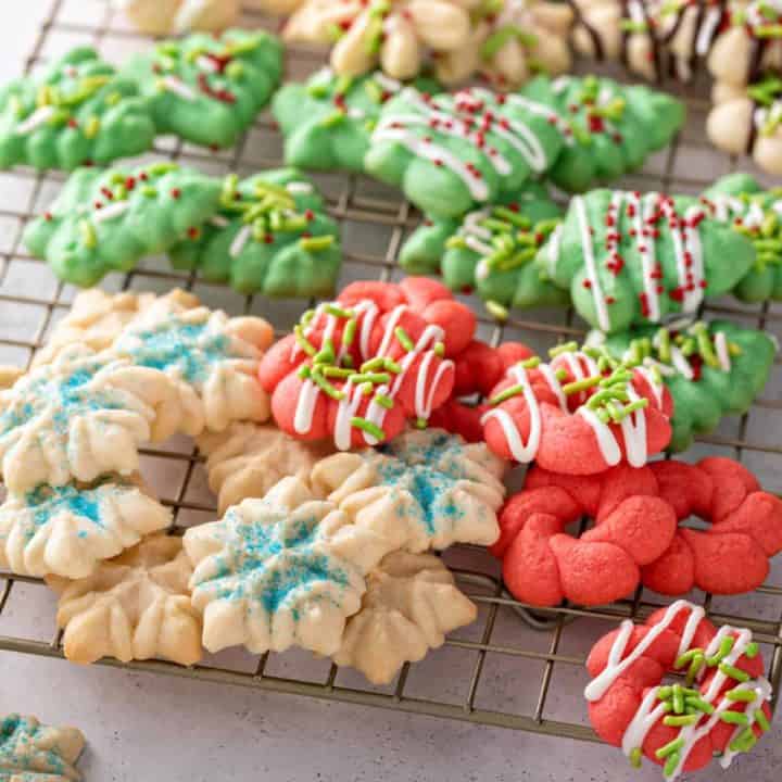 Winter holiday-themed spritz cookies on a wire cooling rack.