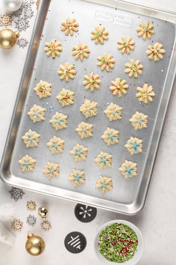 Unbaked spritz cookies on a sheet pan, ready to go in the oven.