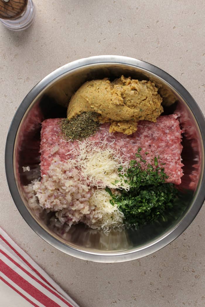 Ingredients for air fryer meatballs in a metal mixing bowl, about to be mixed together.