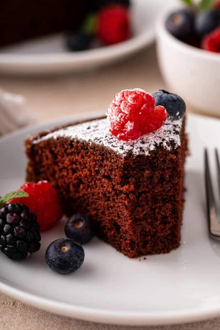 Slice of eggless chocolate cake with several bites taken from it on a white plate.