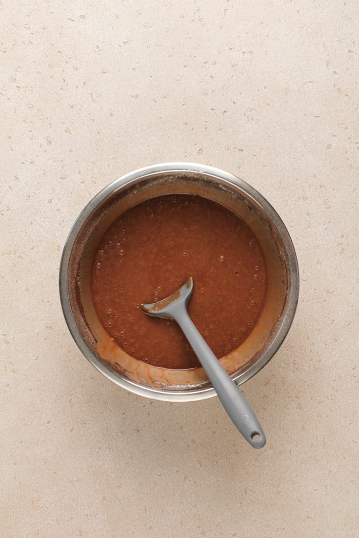 Batter for eggless chocolate cake in a metal mixing bowl.