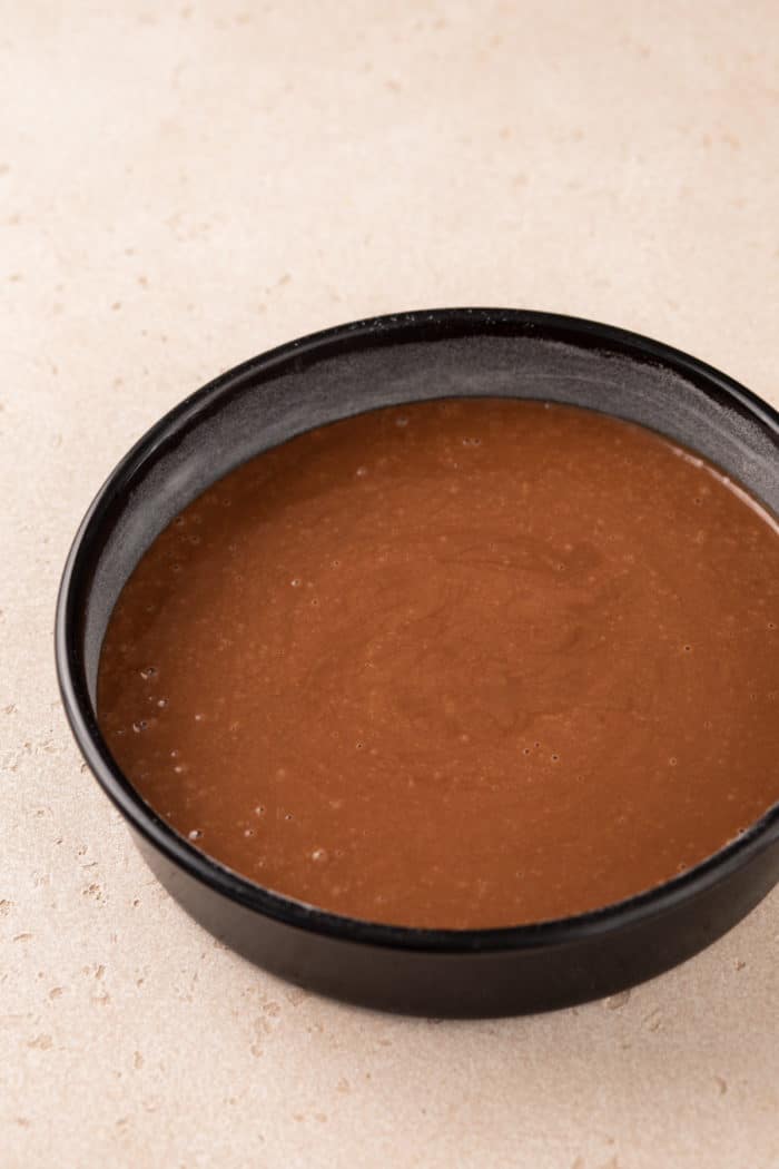 Batter for eggless chocolate cake in a cake pan, ready to go in the oven.