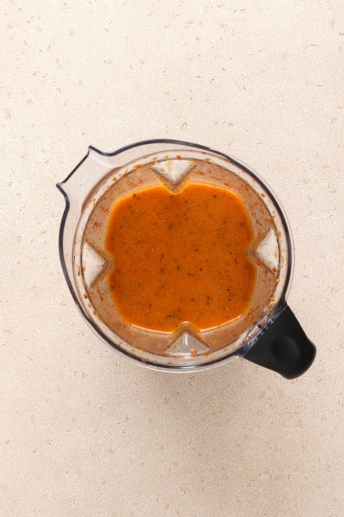 Finished chipotle vinaigrette in the jar of a blender, set on a countertop.