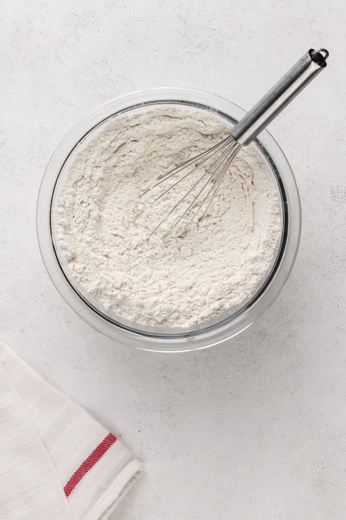 Dry ingredients for kitchen sink cookies being whisked in a glass mixing bowl.