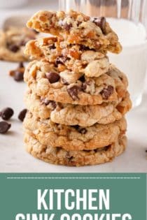 Stack of kitchen sink cookies in front of a glass of milk. The top cookie has been broken in half. Text overlay includes recipe name.