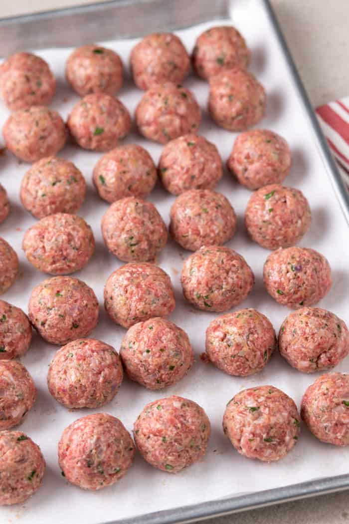 Rolled meatballs on a parchment-lined sheet tray, ready to go in the air fryer.