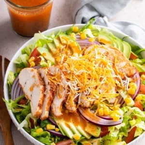 Salad topped with chipotle vinaigrette. A jar of the vinaigrette is in the background.