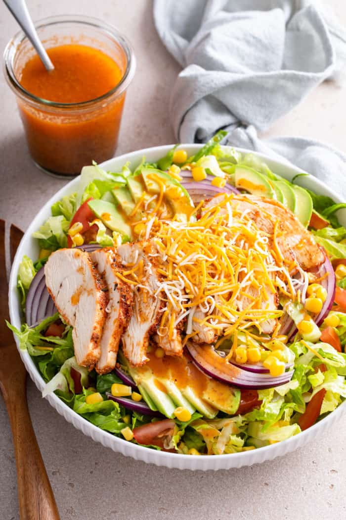 Salad topped with chipotle vinaigrette. A jar of the vinaigrette is in the background.