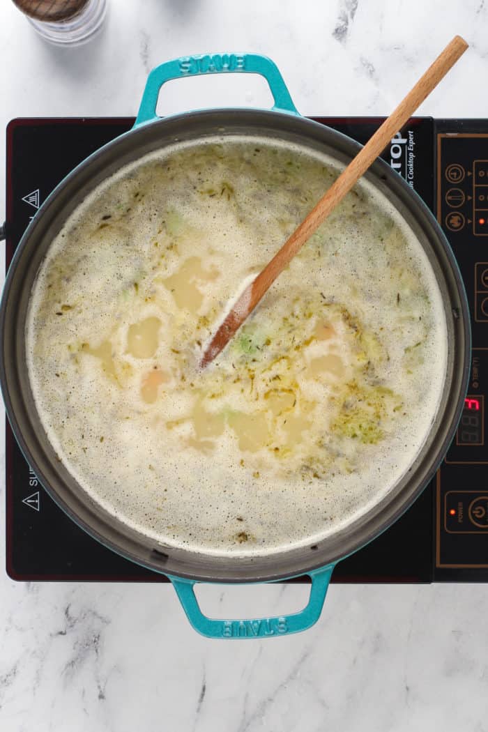 Pot of chicken and wild rice soup simmering on a stove burner.