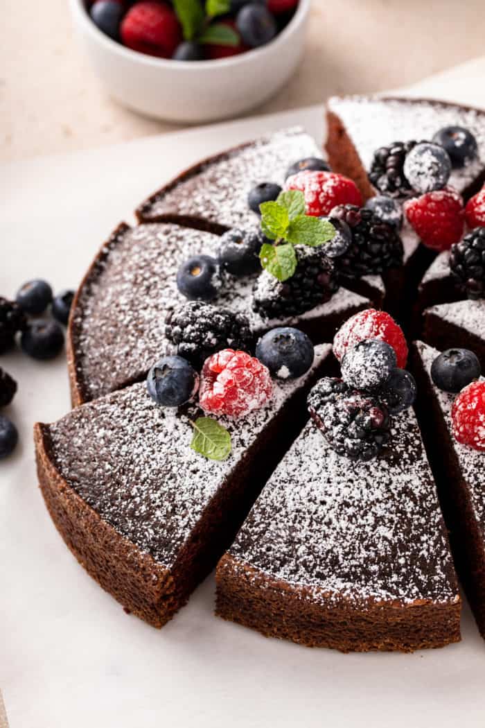 Sliced eggless chocolate cake, dusted with powdered sugar and topped with fresh berries.