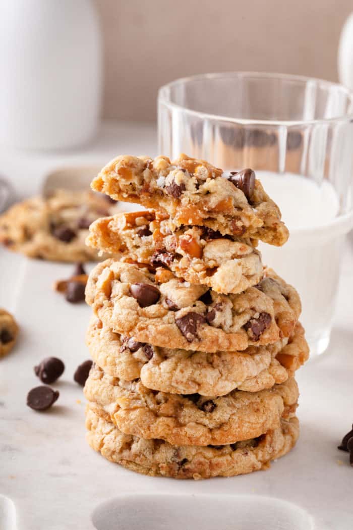 Stack of kitchen sink cookies in front of a glass of milk. The top cookie has been broken in half.