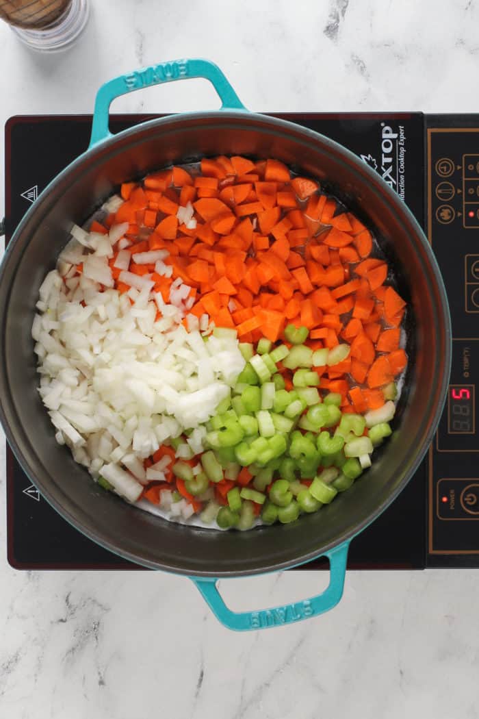 Carrots, onion, and celery in a dutch oven, about to be cooked.