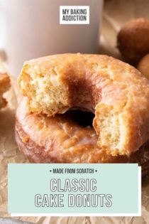 Two cake donuts, one of them broken in half, set next to a white coffee mug. Text overlay includes recipe name.